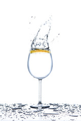 Lemon splashing into glass of water on white background