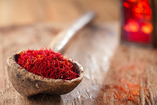 saffron spice in antique wooden spoon on old wood background, cl