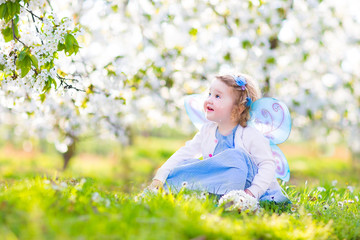 Adorable toddler girl in fairy costume in fruit apple garden