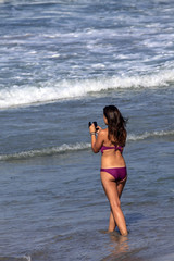 Fototapeta na wymiar junge Frau fotografiert am Strand