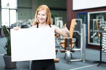 Frau im Fitnessstudio hält Werbetafel
