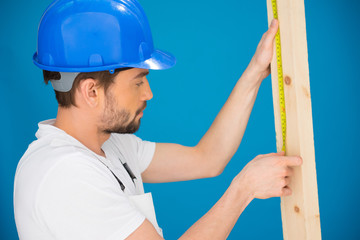 Carpenter or builder measuring a plank of wood
