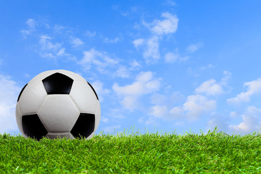 Soccer ball on grass with blue sky