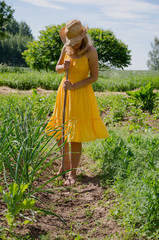 Barefoot woman with  hat grub weed in garden