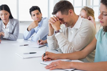 Casual businessman trying not to laugh during meeting