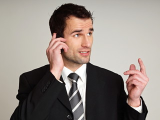 Handsome thinking man in suit with talks at mobile phone