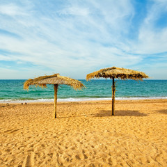 Tropical beach scenery with two straw parasols