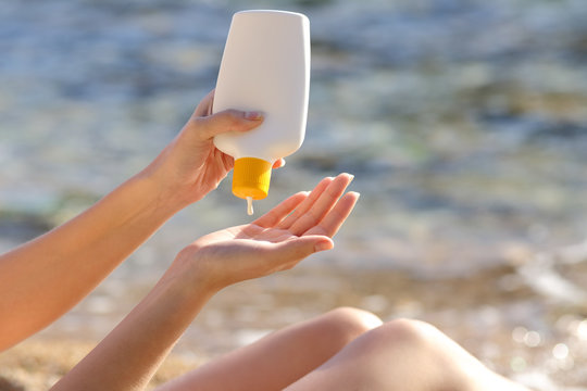 Woman hands putting sunscreen from a bottle on the beach