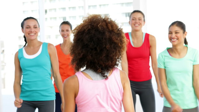 Pretty instructor leading zumba class in fitness studio