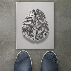 3d metal human brain icon on front of business man feet as conce