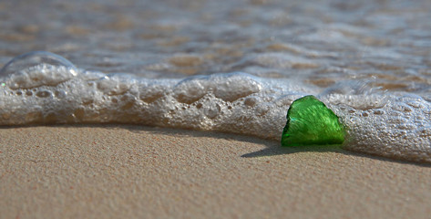 A close up of a heart shaped, single piece of green sea glass