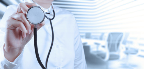Doctor with a stethoscope in the hands and office background