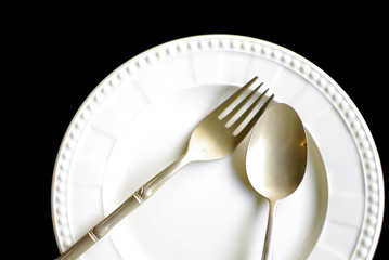 brass spoon and fork on white plate background