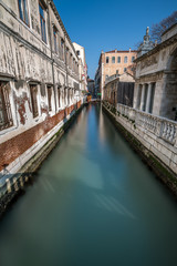 Fototapeta na wymiar Narrow Canal Among Old Colorful Brick Houses in Venice, Italy