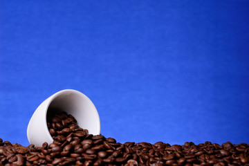 White cup with coffee beans on a blue background