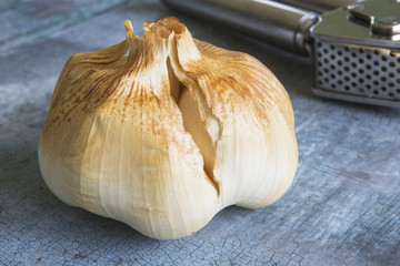 Bulb Of Smoked Garlic On Wooden Surface With Press
