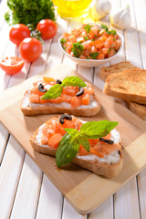 Delicious bruschetta with tomatoes on cutting board close-up