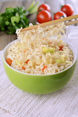 Tasty instant noodles with vegetables in bowl on table close-up
