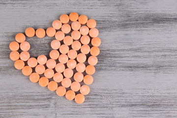 Heart of pills on wooden background