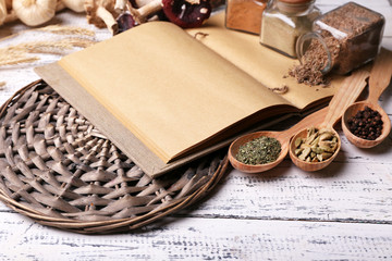 Fototapeta na wymiar Different spices and cook book on wooden table, close up