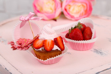 Tasty cup cake with cream on wooden chair