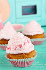 Tasty cup cakes with cream on blue wooden table