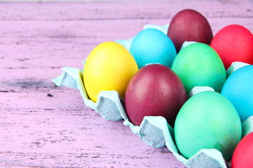 Colorful Easter eggs in tray on wooden background