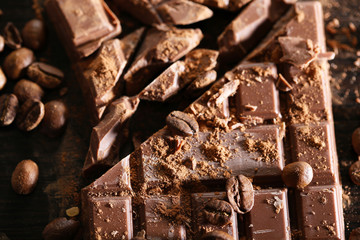 Chopped bar of chocolate on wooden background