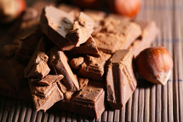 Chopped bar of chocolate on bamboo mat background