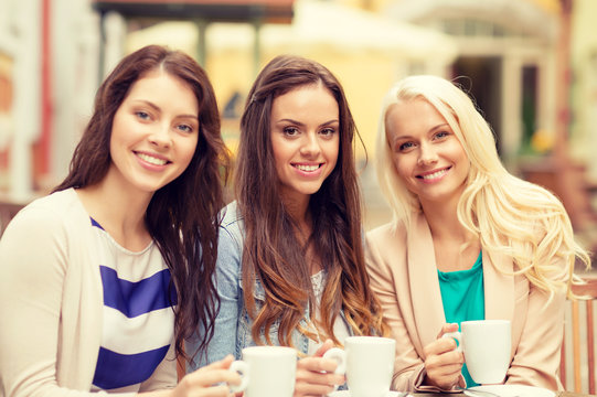 three beautiful girls drinking coffee in cafe