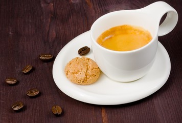 cup of espresso coffee and biscuit near coffee beans