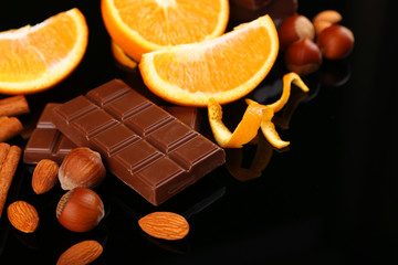 Chocolate, orange and nuts on black background
