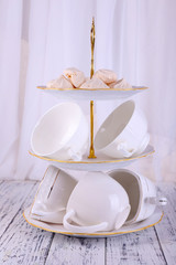 Cups in vase on table on bright background