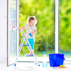 Little girl washing a window