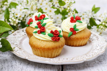 Beautiful rose cupcakes and bird cherries in the background