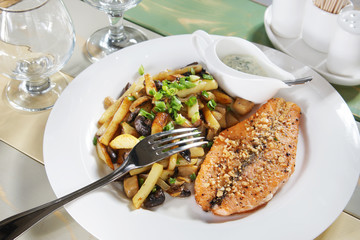 Piece of fried fish with potatoes on a laid table