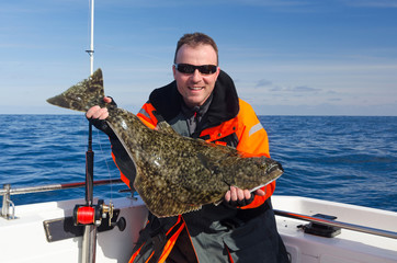 Happy angler with halibut fish - 64462485