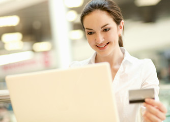 Happy woman sitting on the desk and shopping online