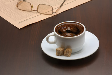 cup of coffee near the laptop and newspapers.