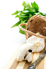 Mushrooms in wicker basket,greens and knife with copy-space