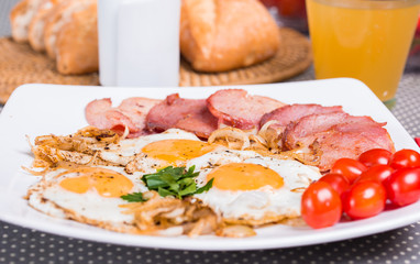 Breakfast with fried eggs beacon onion and fresh tomatoes