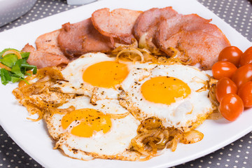 Breakfast with fried eggs beacon onion and fresh tomatoes