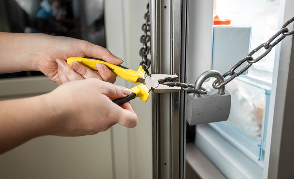 photo of woman trying to cut chain on fridge with pliers