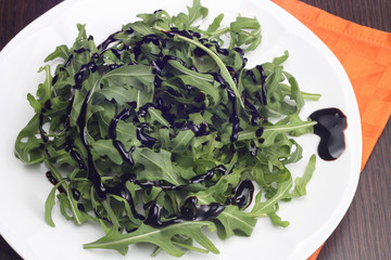 Rocket salad with balsamic vinegar on white plate