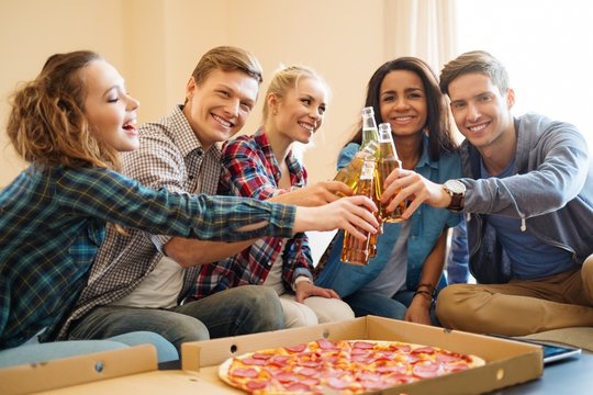 Group of multi ethnic friends with pizza and bottles of drink 