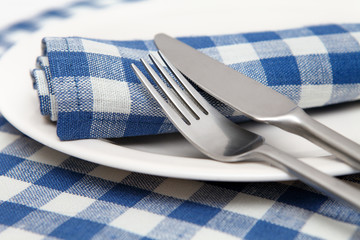 Napkins in blue checked with a knife, fork and plate closeup