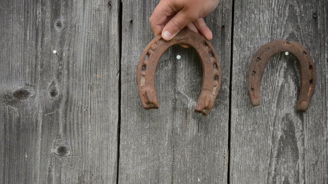 hand hang retro rusty horse shoe on old wooden rural house wall