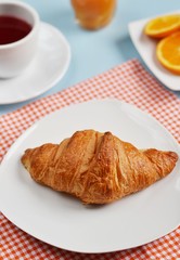 Croissants on a white plate with tea and orange juice