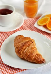 Croissants on a white plate with tea and orange juice