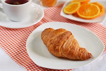Croissants on a white plate with tea and orange juice